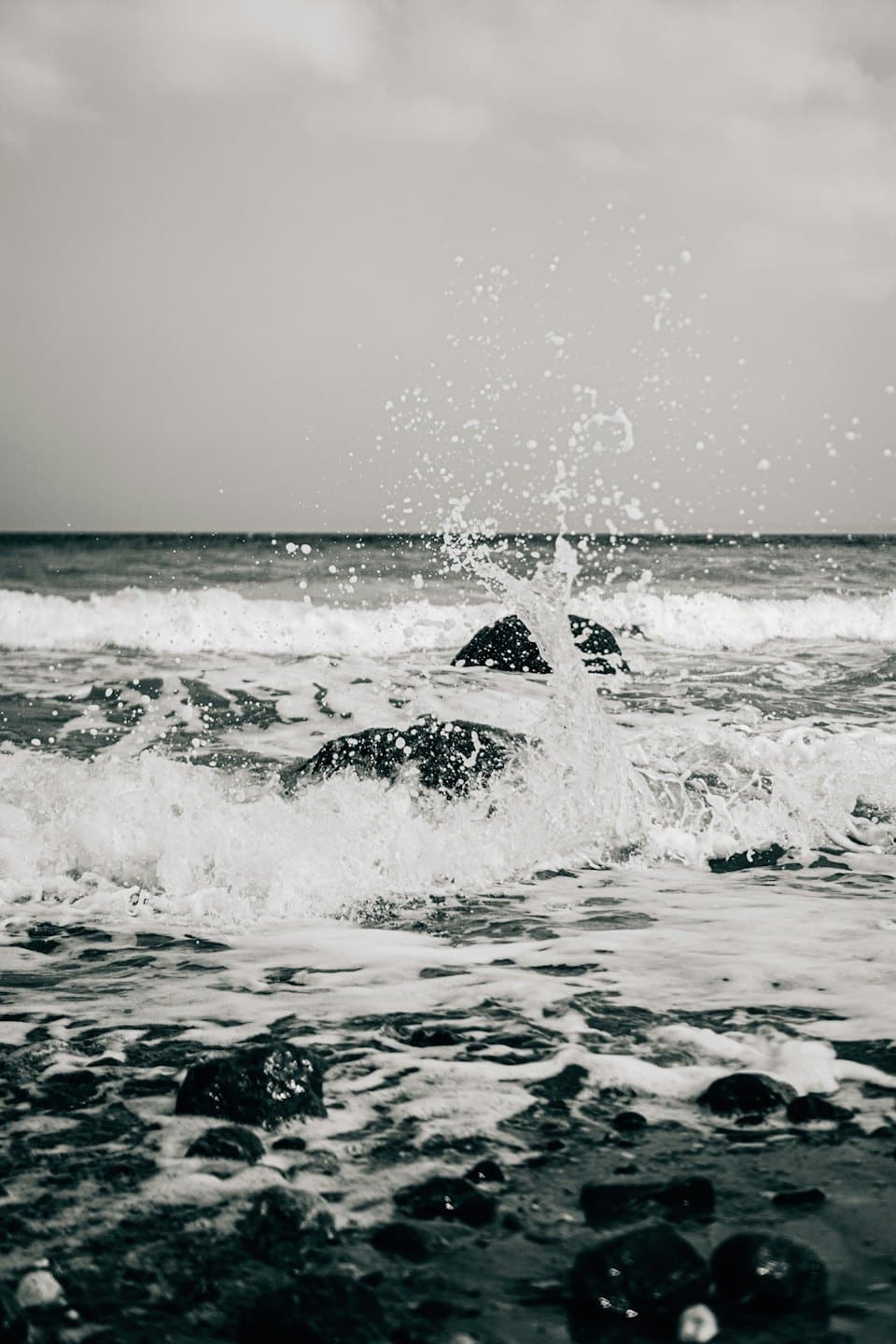 Onde dell'oceano si infrangono su rocce scure e bagnate.