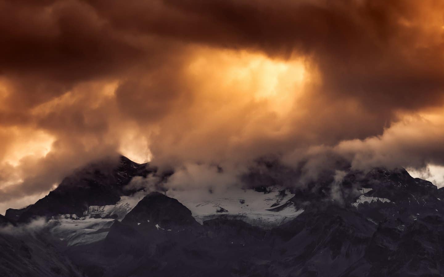 Cime innevate che emergono da fitte nuvole ondulate.
