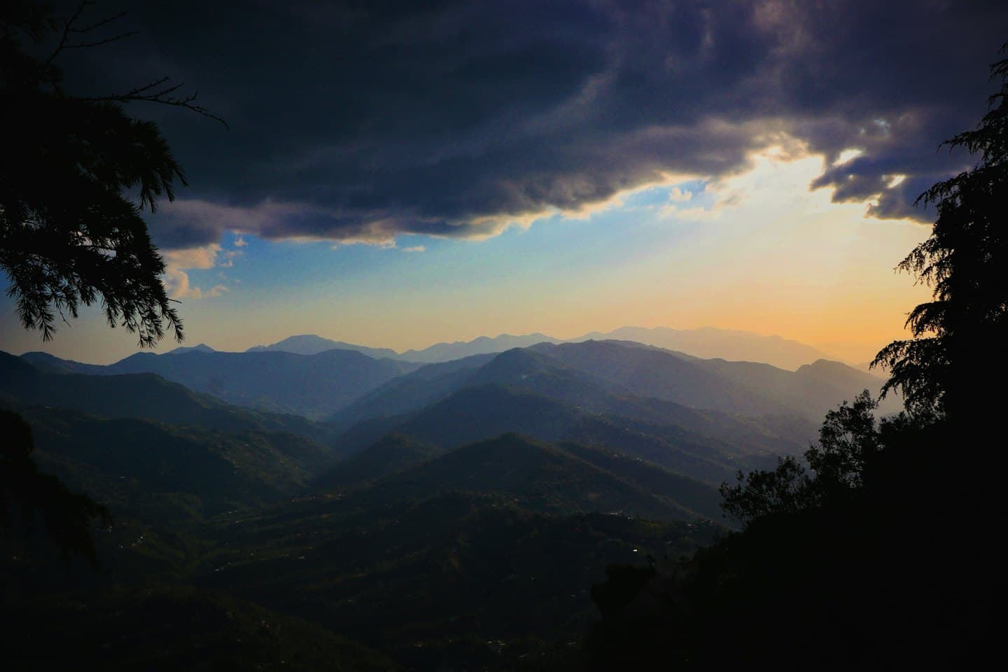 La luce del sole filtra tra i pini stagliati, illuminando le cime nebbiose delle montagne.